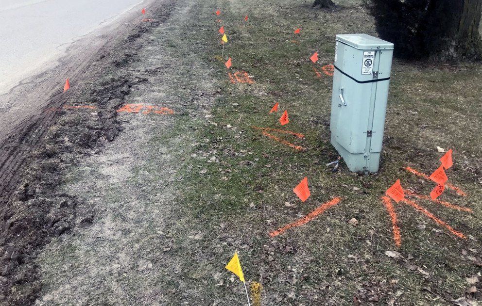 Telecommunication lines marked with orange flags and existing gas line marked with yellow flags
