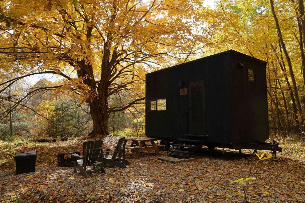 Outside of a Getaway Barber Creek campground cabin that is covered in leaves.